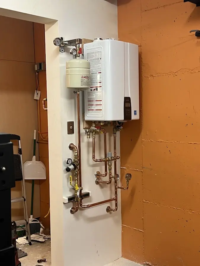 Plumbing technician inspecting water heater connections in West Providence